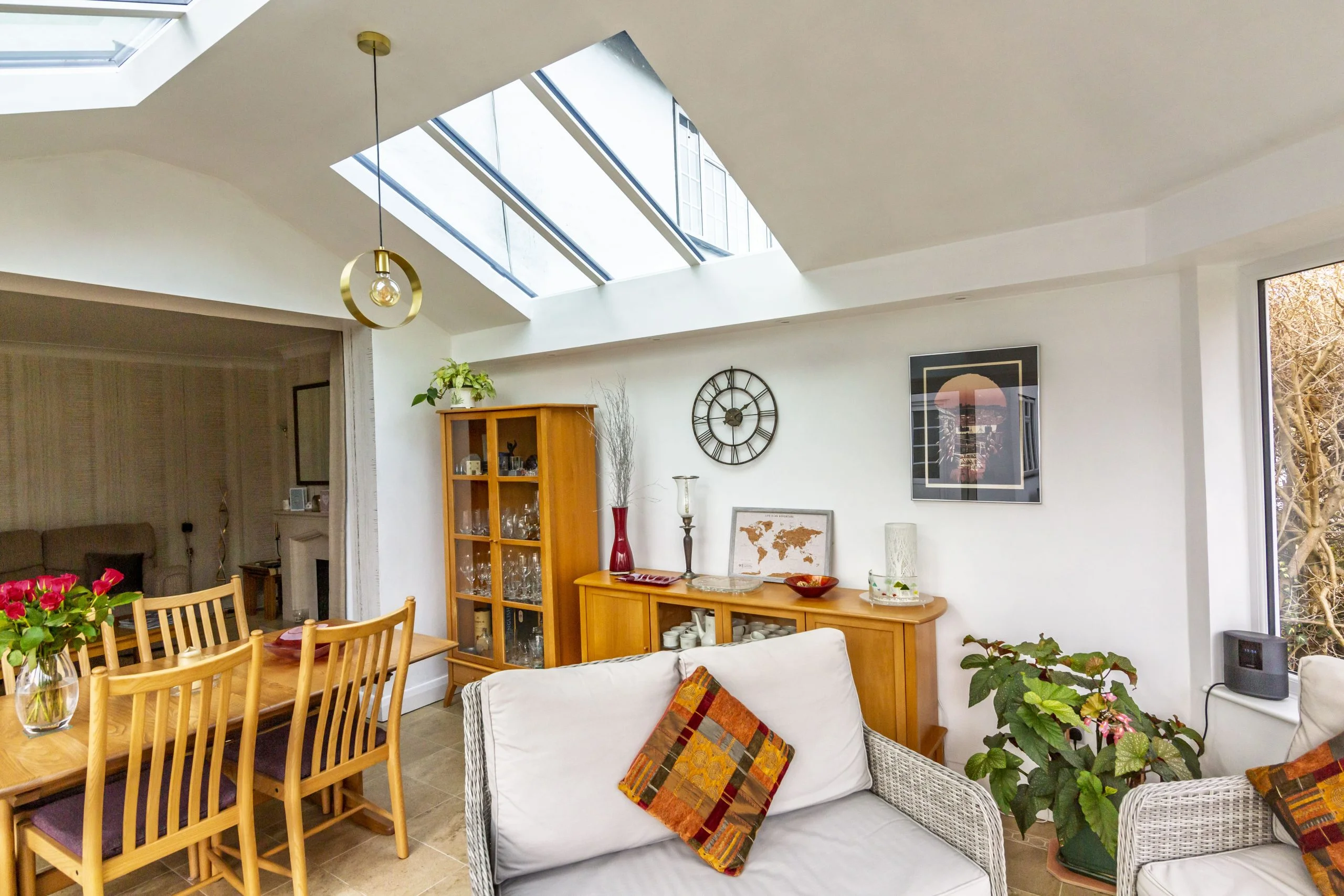Homely lounge area with glass panels on roof, furnished with wooden oak dining table and chairs.
