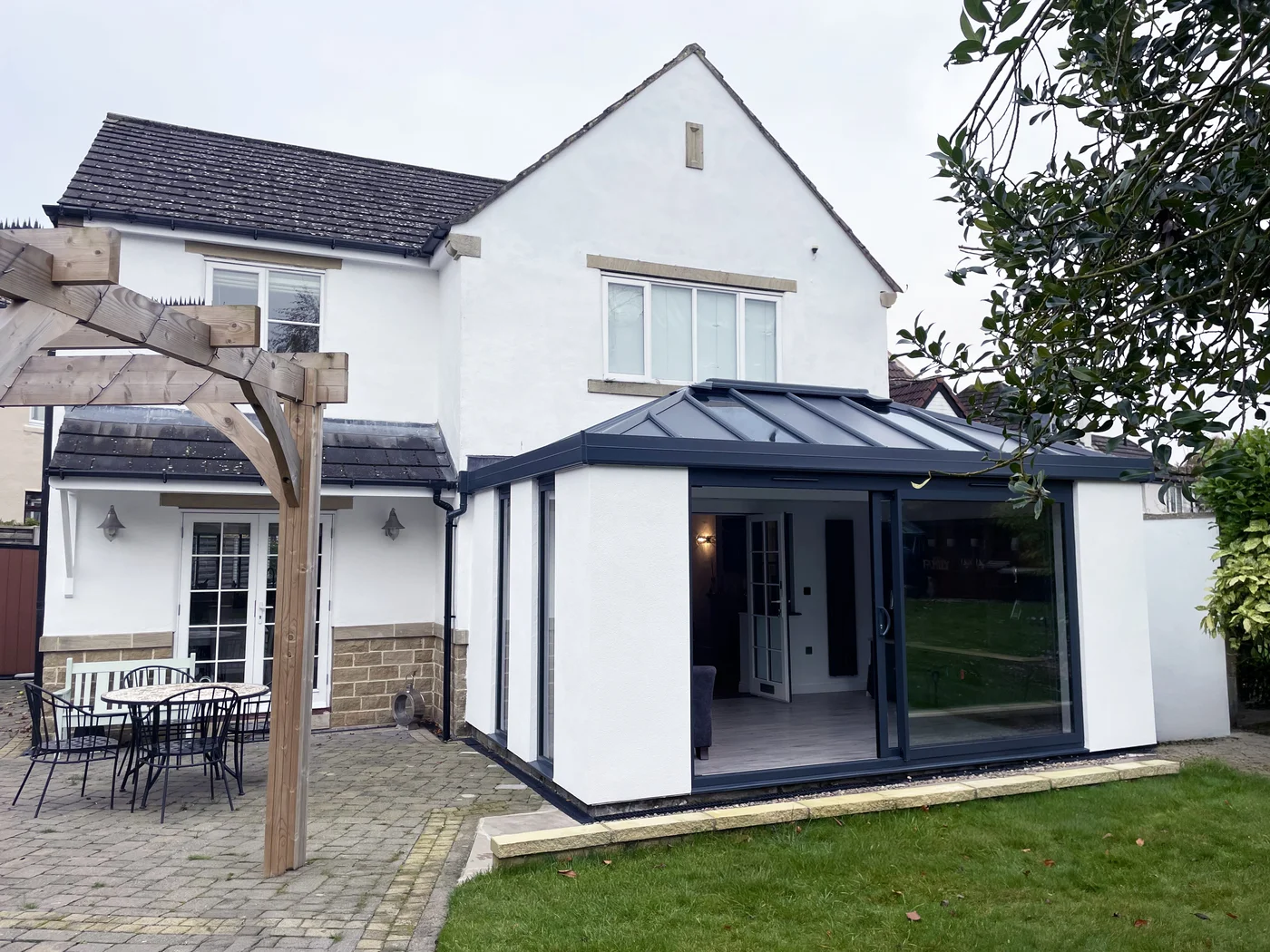 Back of UK home with spacious conservatory extension in white rendering and glass bi-fold doors