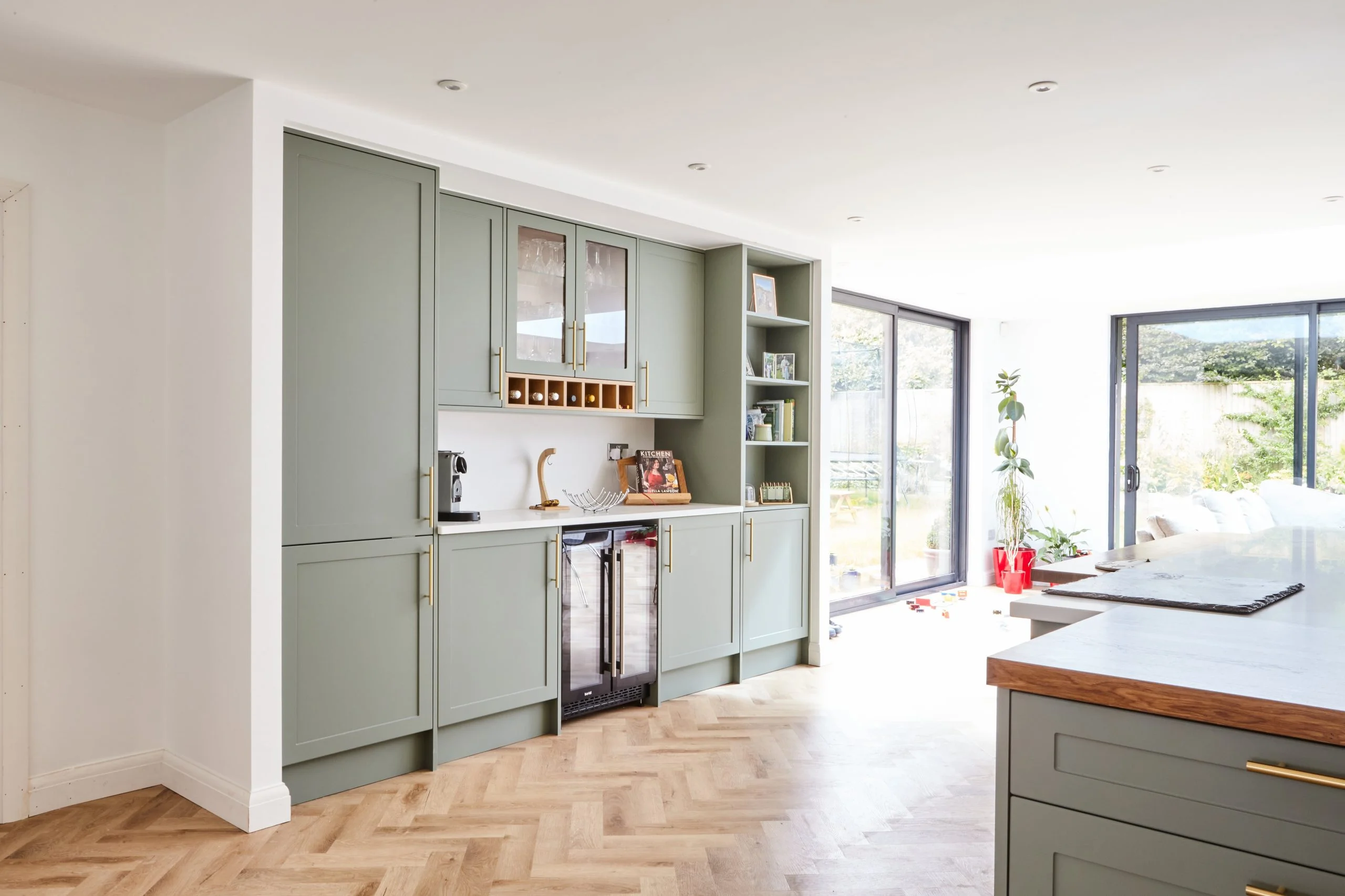Luxury modern kitchen with green cupboards, herringbone floors and island feature