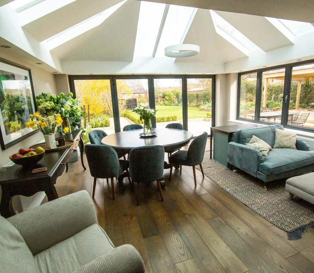 Wide angle view of living room interior with extension, furnished with round wooden dining table and sofa