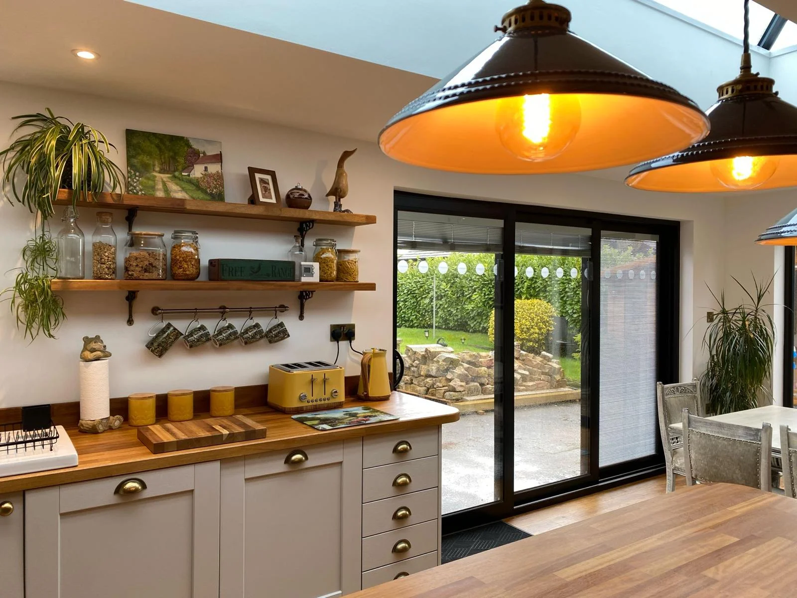 Warm kitchen ceiling light hanging over island, with background of wood counters and grey cupboards