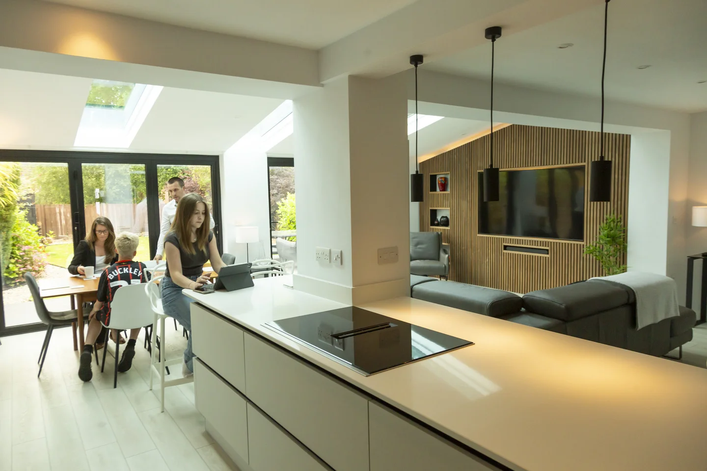 Family sitting on dining table in modern kitchen with white countertops