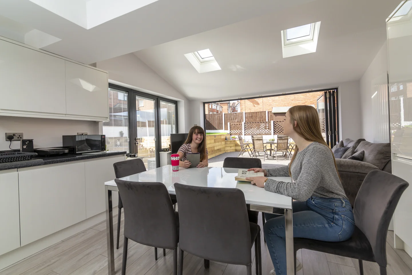Women sitting together in kitchen dining room talking and reading