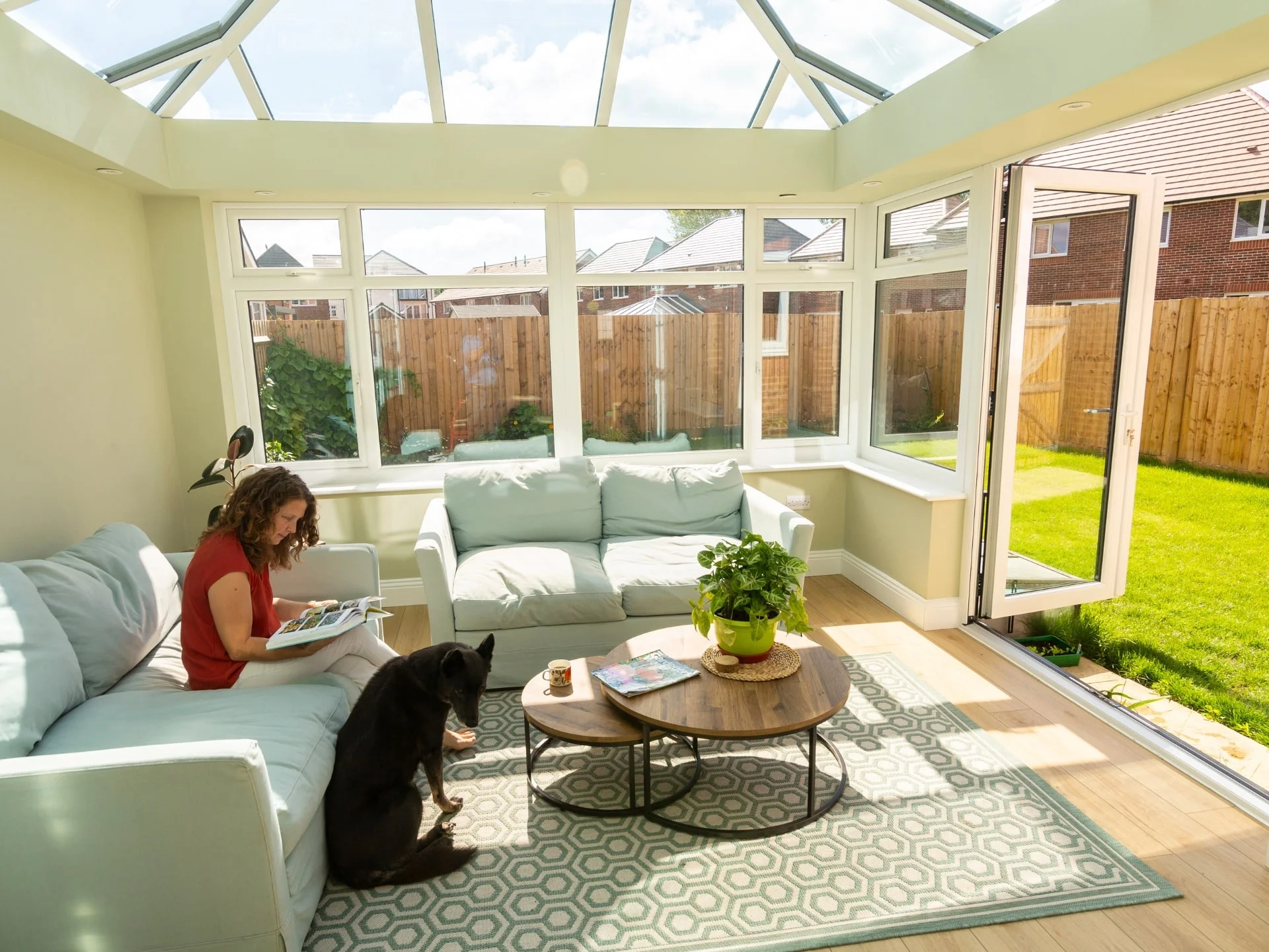 Mature woman sitting down reading in conservatory with German Shephard