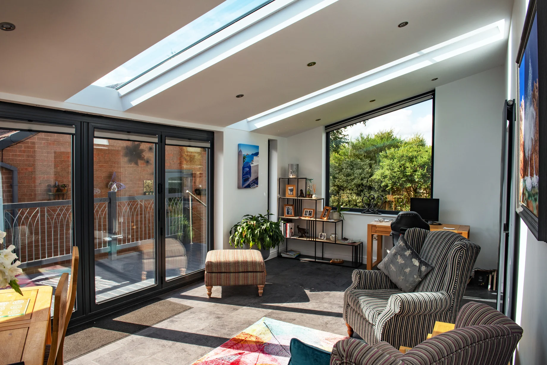 Sunny and bright indoor view of home extension with comfy lounge chairs and decor