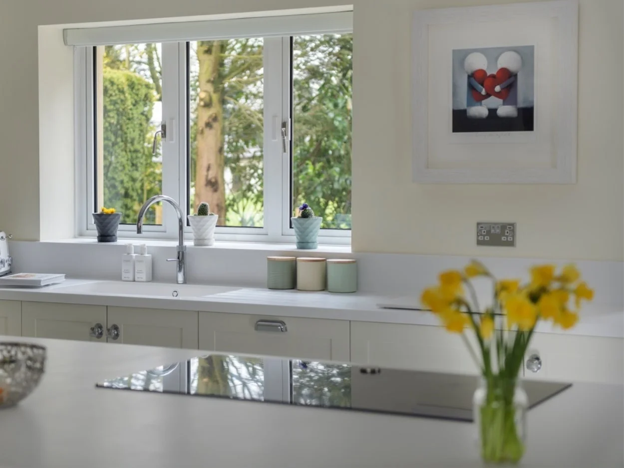 White kitchen counter and cooking hob with yellow daffodils in vase