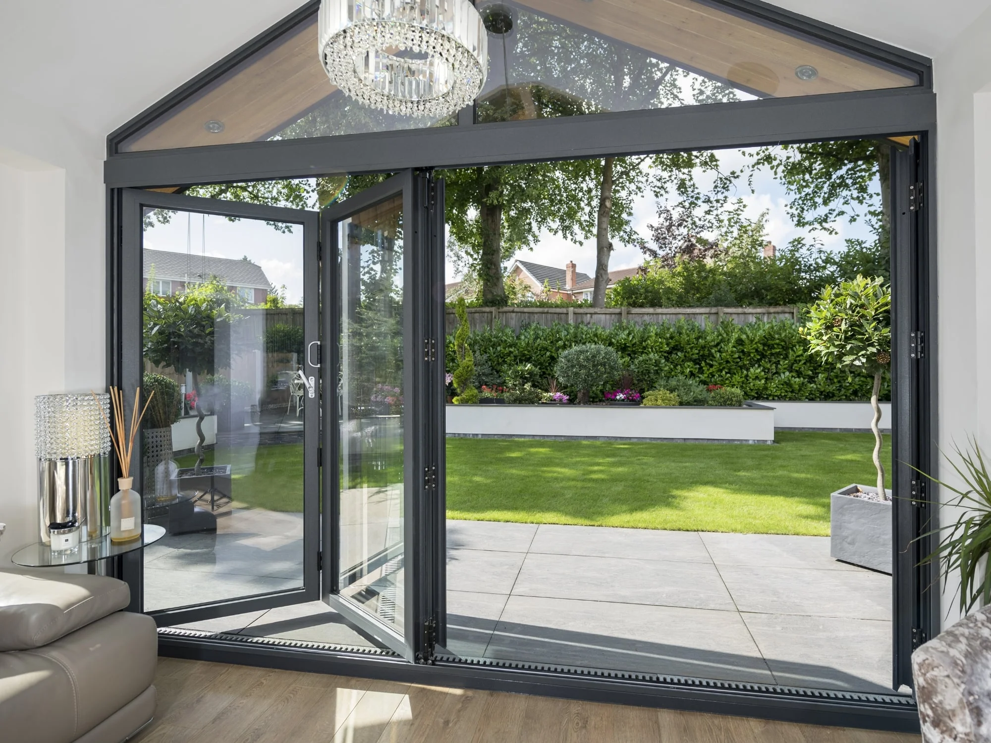 Large bi-folding doors opening to sleek, modern patio and lawn